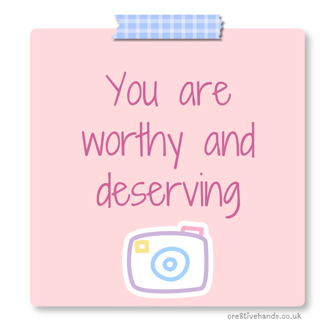 Pastel pink sticky note with the message “You are worthy and deserving” with blue gingham tape and a camera doodle.